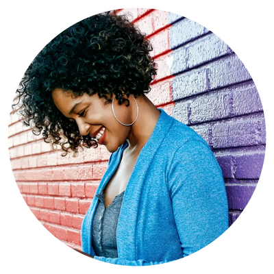 woman in large hoop earrings wearing a blue sweater looking down and smiling