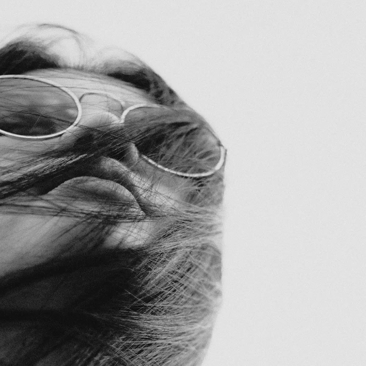 Close-up of a person wearing sunglasses with hair covering their face with a blurred background